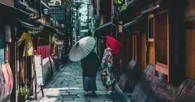 Couple walking on street while holding umbrella in Kyoto