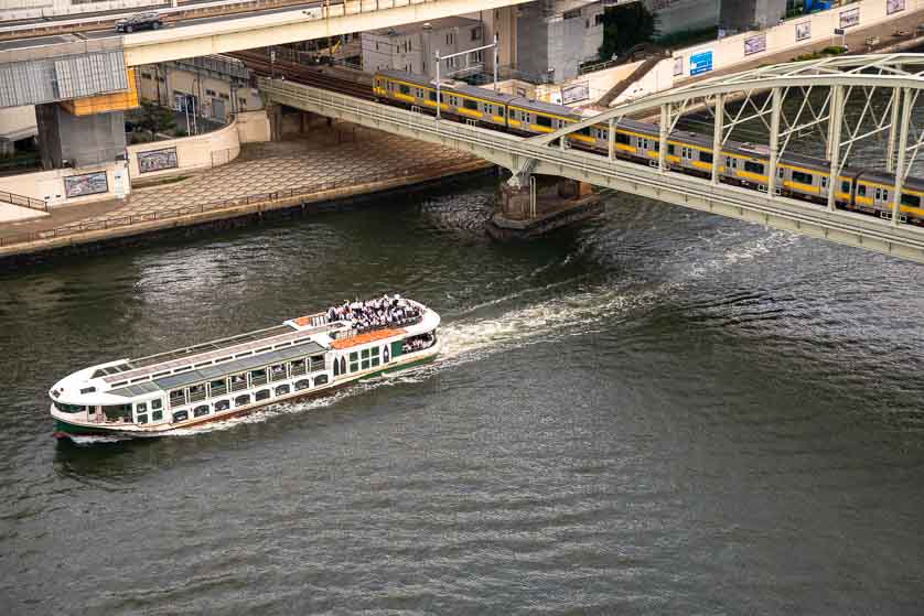 A cruise boat goes under a train crossing Ryogoku Bridge, Sumida River, Tokyo.